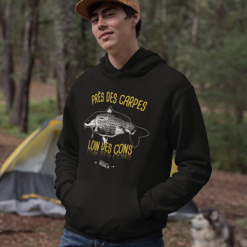 Photo d'un jeune homme portant un Sweat à capuche Près des Carpes Loin des Cons - Cadeau Carpiste Homme Femme - Noir